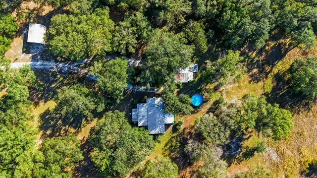 an aerial view of residential houses with outdoor space and trees