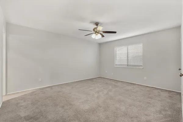 an empty room with windows and chandelier fan