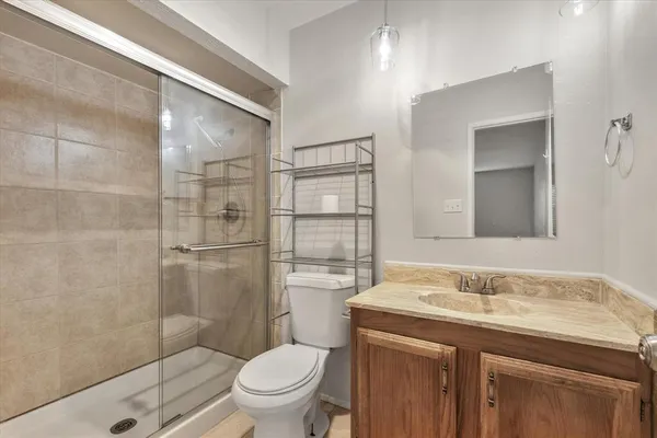 a bathroom with a granite countertop sink toilet a mirror and shower