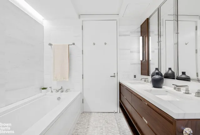 a bathroom with a double vanity sink a mirror and a bathtub