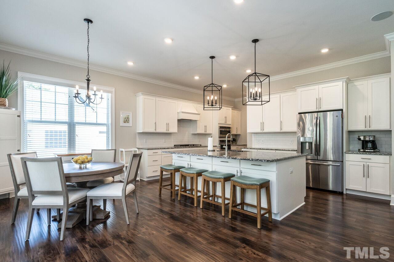 3034 Adonis Circle Raleigh, NC 27612 - Photo 12 of 46 a kitchen with stainless steel appliances kitchen island granite countertop a dining table chairs and wooden floor