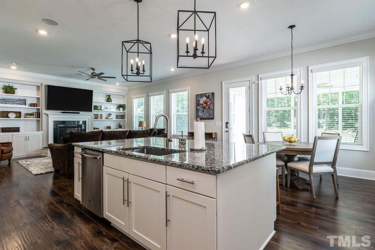 3034 Adonis Circle Raleigh, NC 27612 - Photo 15 of 46 a kitchen with stainless steel appliances granite countertop a stove top oven a dining table and chairs with wooden floor