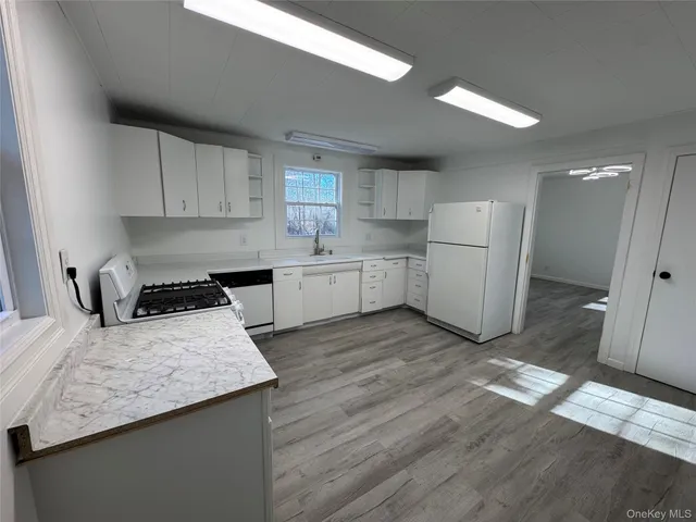 a kitchen with a sink a stove a refrigerator and white cabinets