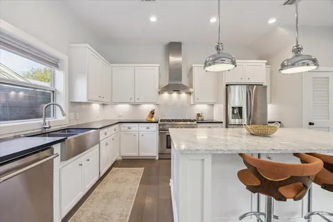 a kitchen with stainless steel appliances granite countertop a sink a stove a refrigerator and island with wooden floor