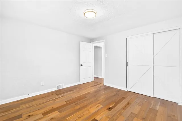 an empty room with wooden floor and fan