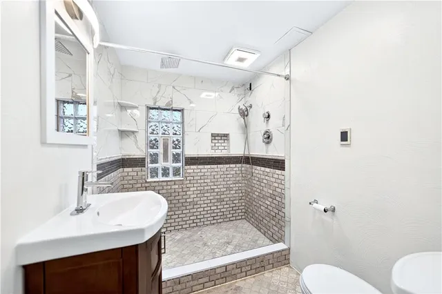 a bathroom with a sink a toilet a mirror and shower