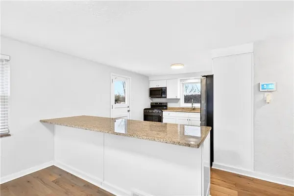 a large kitchen with kitchen island a sink wooden floor and a refrigerator