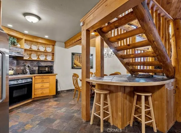 a kitchen with a stove a refrigerator and chairs