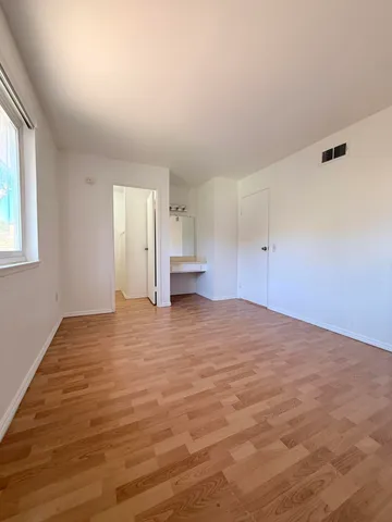 a view of empty room with wooden floor and window
