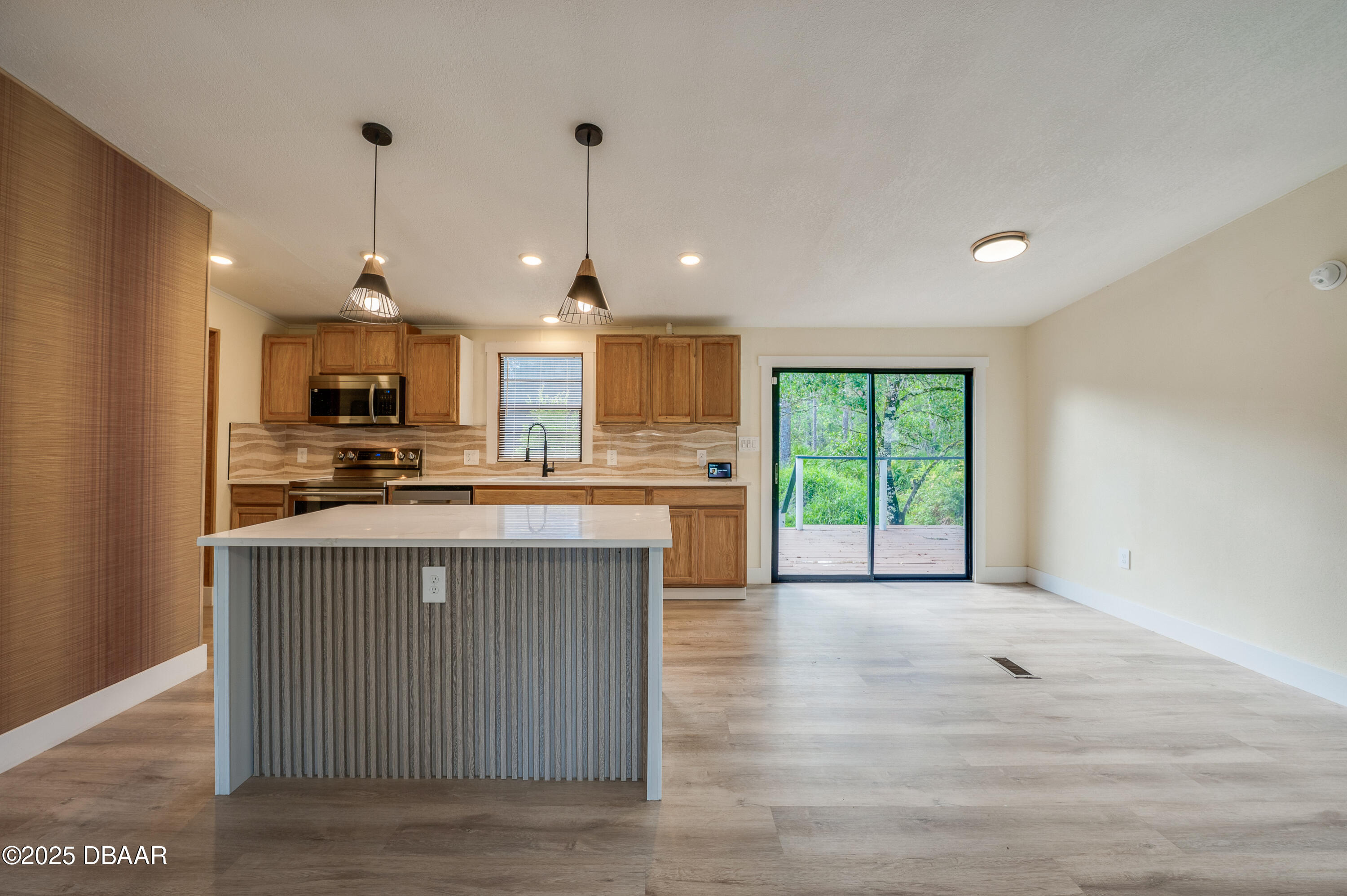3669 General Marshall Road Daytona Beach, FL 32124 - Photo 11 of 32 a open kitchen with stainless steel appliances granite countertop a stove a sink a refrigerator and a dining table with wooden floor