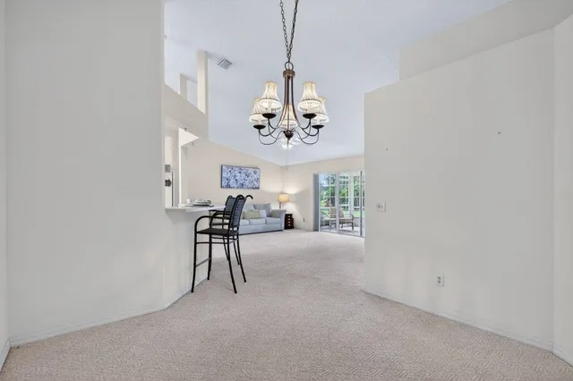 an empty room with chandelier fan and windows