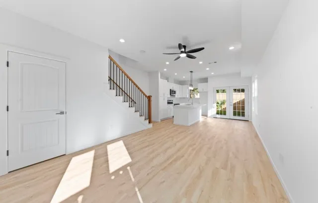 a view of an empty room with wooden floor and a kitchen