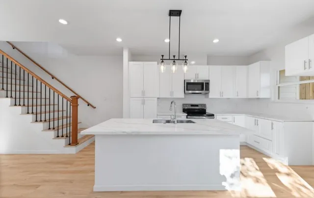 a kitchen with kitchen island white cabinets stainless steel appliances and wooden floor