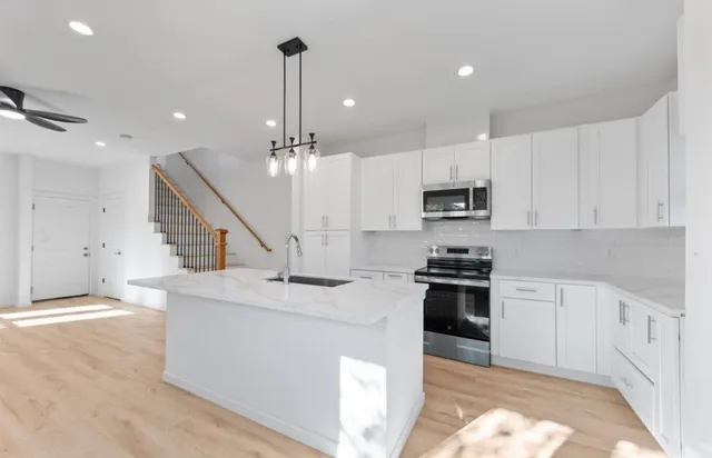 a kitchen with stainless steel appliances kitchen island granite countertop a stove a sink and a refrigerator