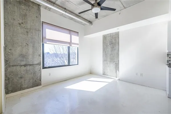 an empty room with windows and fan