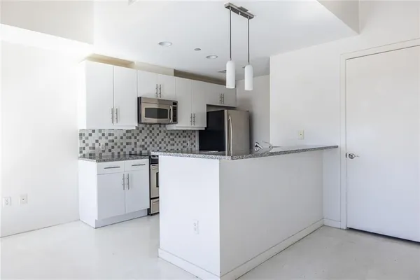a kitchen with stainless steel appliances granite countertop a sink and a refrigerator