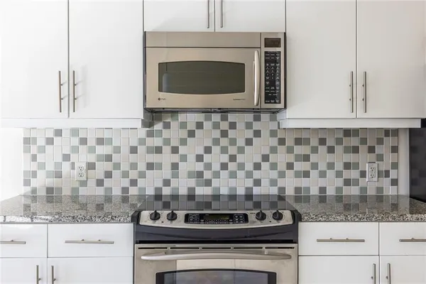 a kitchen with granite countertop a stove and a microwave