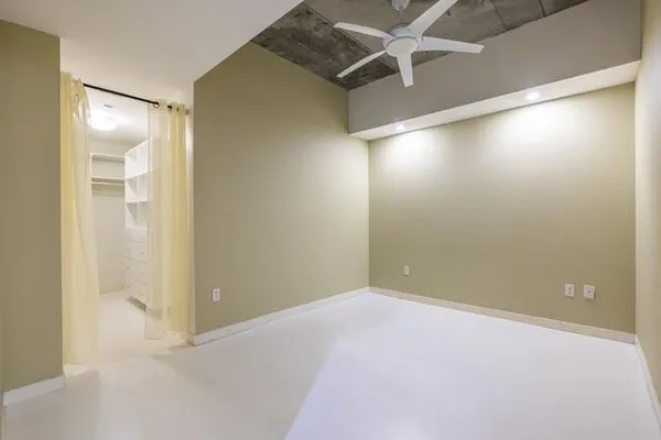 an empty room with windows and fan