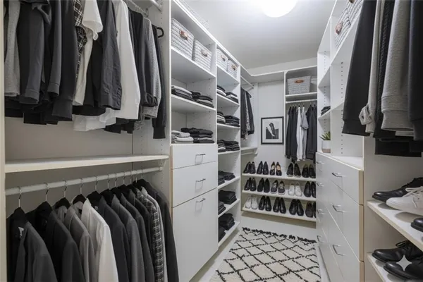 a view of walk in closet with clothes and shoes