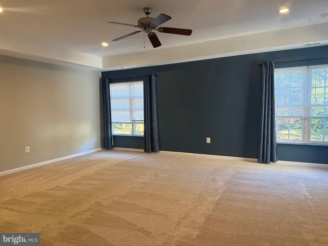 a view of an empty room with a window and a kitchen