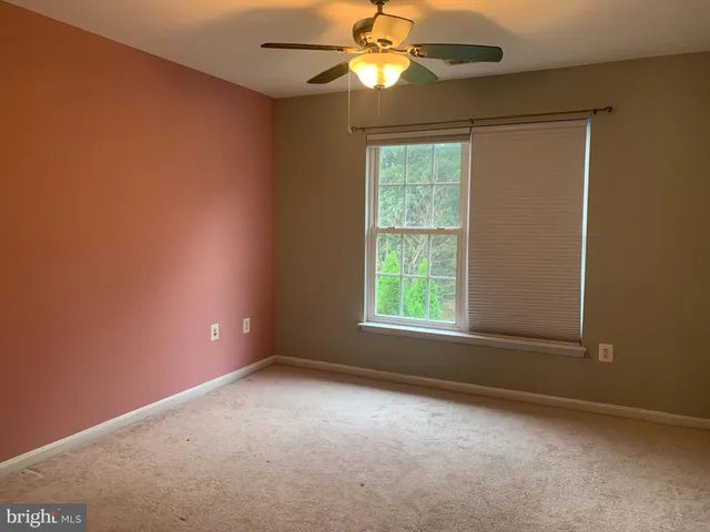 an empty room with a window and a fan