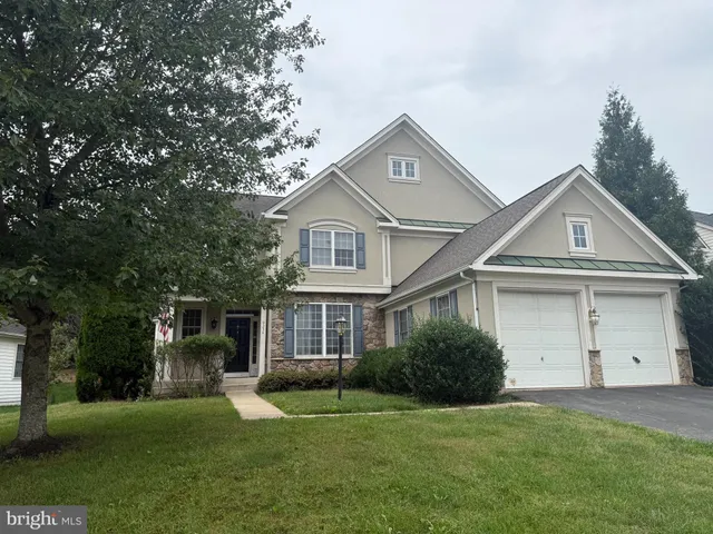 a front view of a house with a garden and trees