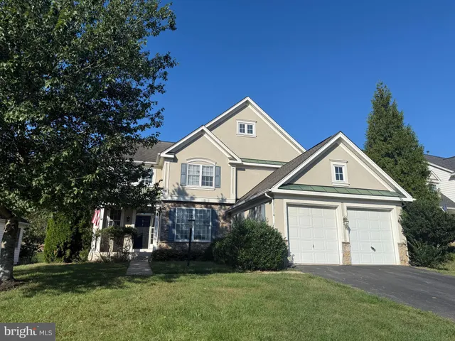 a view of house with a big yard and large trees