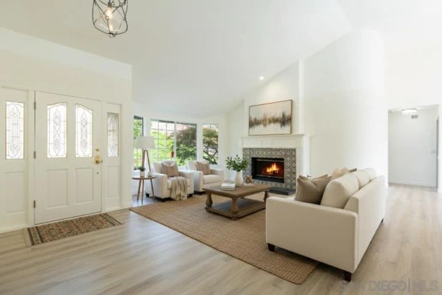 a view of an empty room with wooden floor fireplace and a window