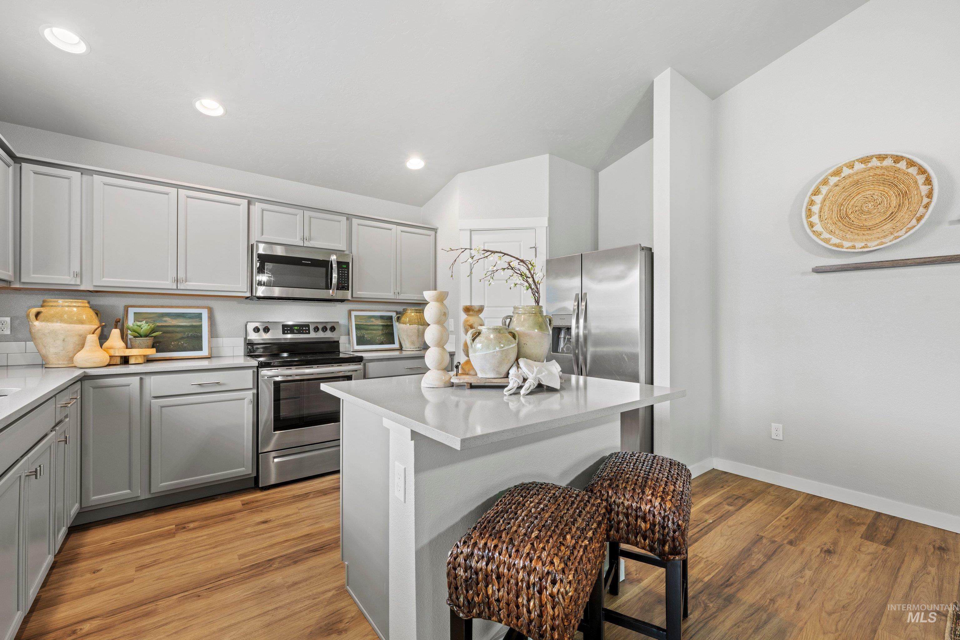 12744 West Fig Street Boise, ID 83713 - Photo 13 of 34 Kitchen featuring light gray cabinetry, stainless steel appliances, a white subway tile backsplash, and wood-finish flooring