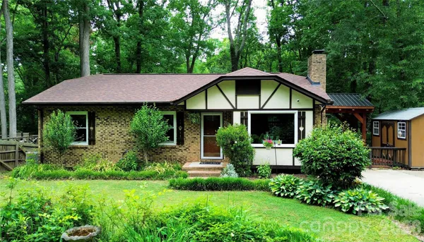 a front view of a house with a yard potted plants and a bench