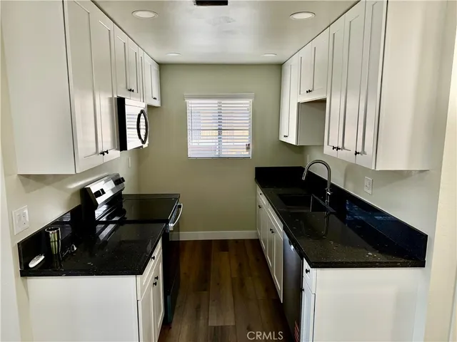 a kitchen with granite countertop a sink a stove and cabinets