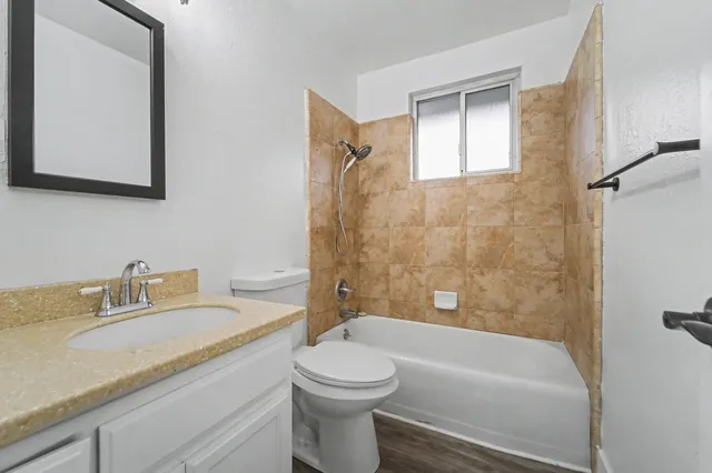 a bathroom with a granite countertop sink a toilet and shower