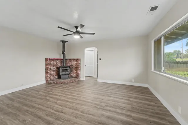 a view of an empty room with a window and wooden floor