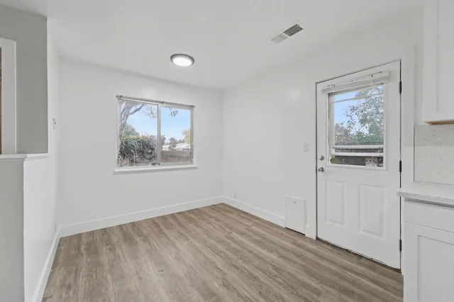 a view of an empty room with wooden floor and a window