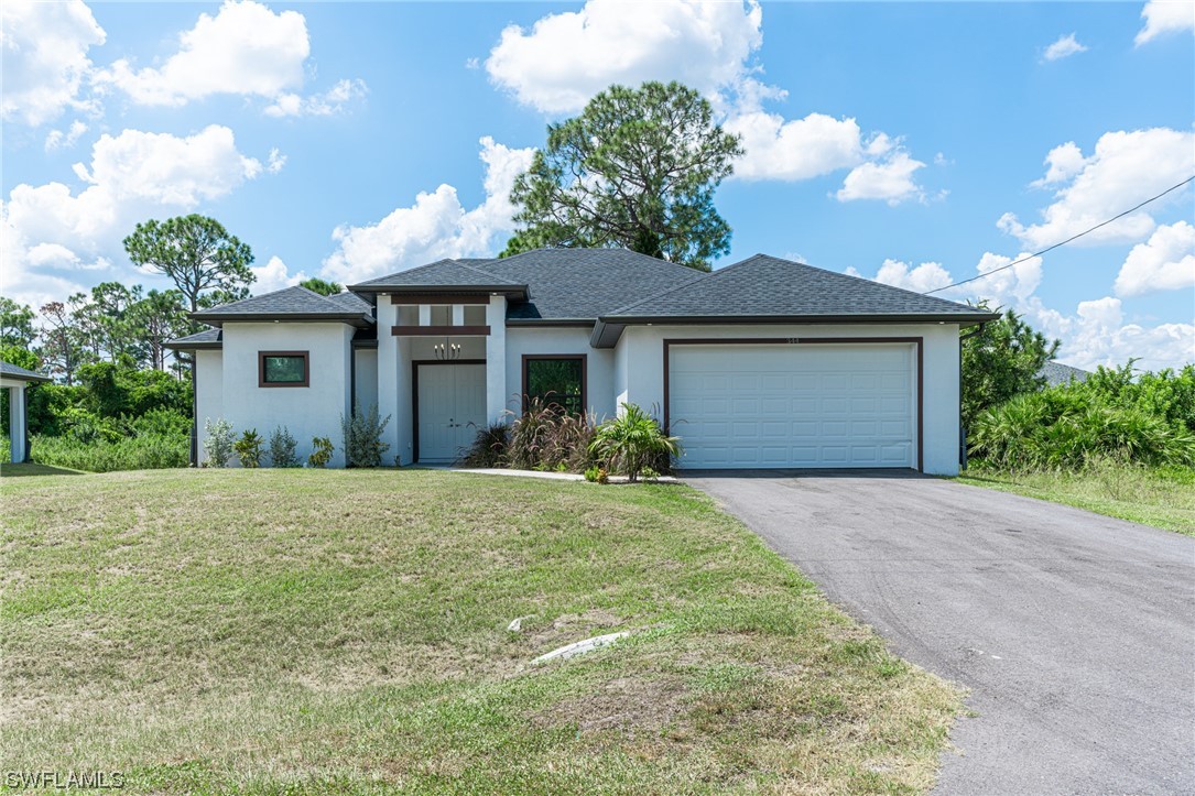 a front view of house with yard and trees in the background