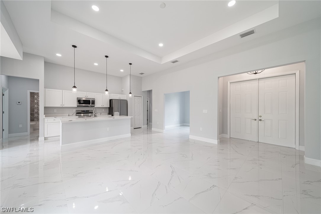 344 Rancho Avenue Lehigh Acres, FL 33974 - Photo 5 of 27 a large white kitchen with kitchen island a sink a stove and a refrigerator