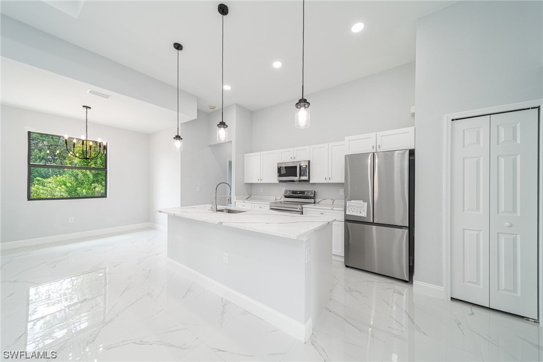 344 Rancho Avenue Lehigh Acres, FL 33974 - Photo 6 of 27 a kitchen with stainless steel appliances kitchen island a table chairs refrigerator and microwave