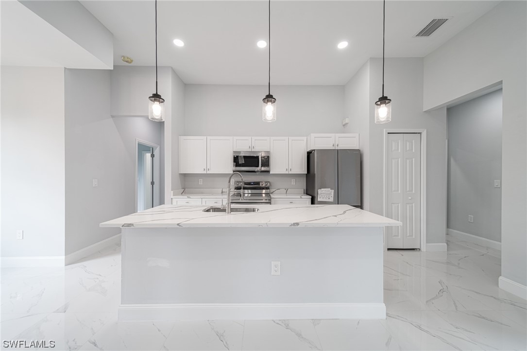 344 Rancho Avenue Lehigh Acres, FL 33974 - Photo 7 of 27 a large kitchen with stainless steel appliances kitchen island a large island in the center