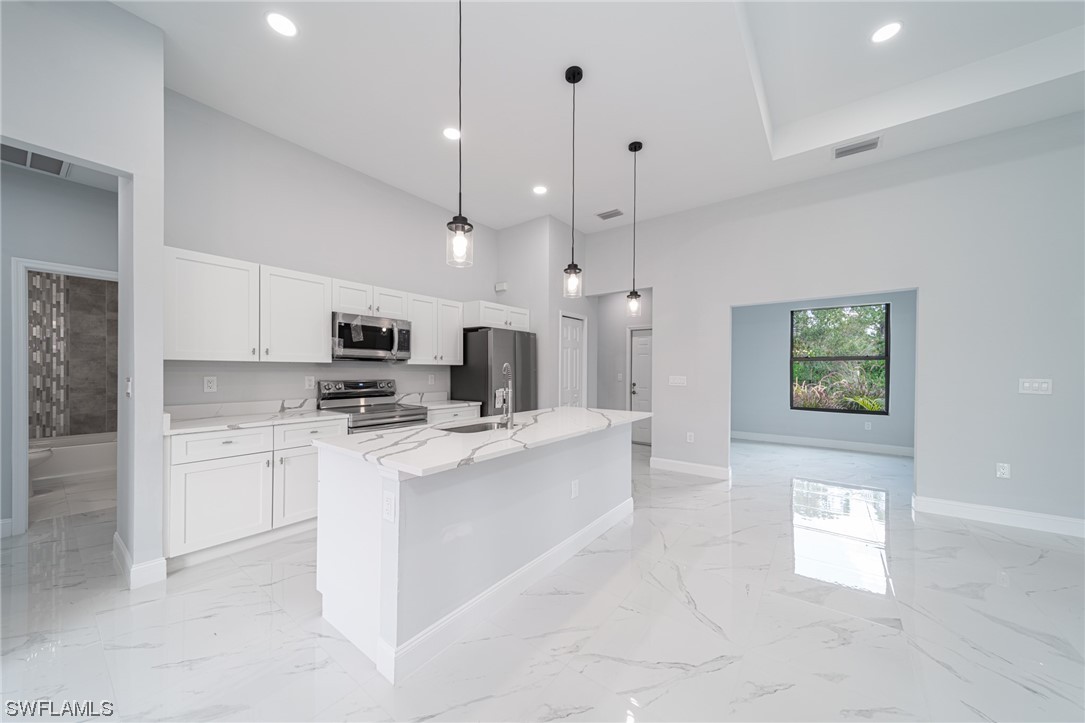 344 Rancho Avenue Lehigh Acres, FL 33974 - Photo 8 of 27 a large white kitchen with kitchen island a sink a stove a refrigerator and a cabinets