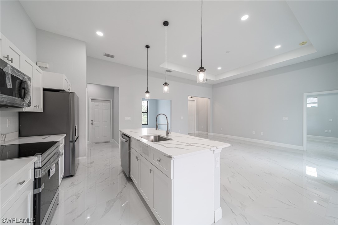 344 Rancho Avenue Lehigh Acres, FL 33974 - Photo 9 of 27 a kitchen with stainless steel appliances kitchen island a sink a stove a microwave a center island and cabinets