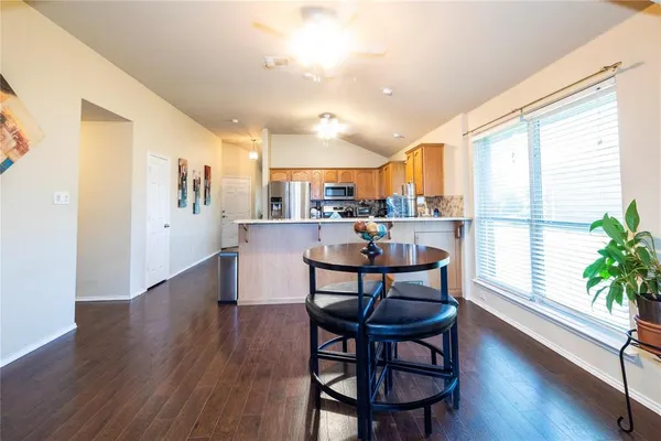 a kitchen with stainless steel appliances a dining table chairs and wooden floor
