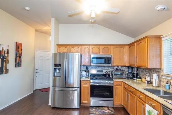 a kitchen with stainless steel appliances granite countertop a refrigerator and a stove top oven