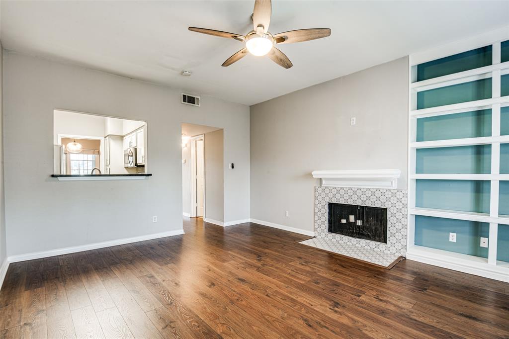 9801 Royal Lane, Unit 711 Dallas, TX 75231 - Photo 9 of 23 an empty room with wooden floor a fireplace and a ceiling fan