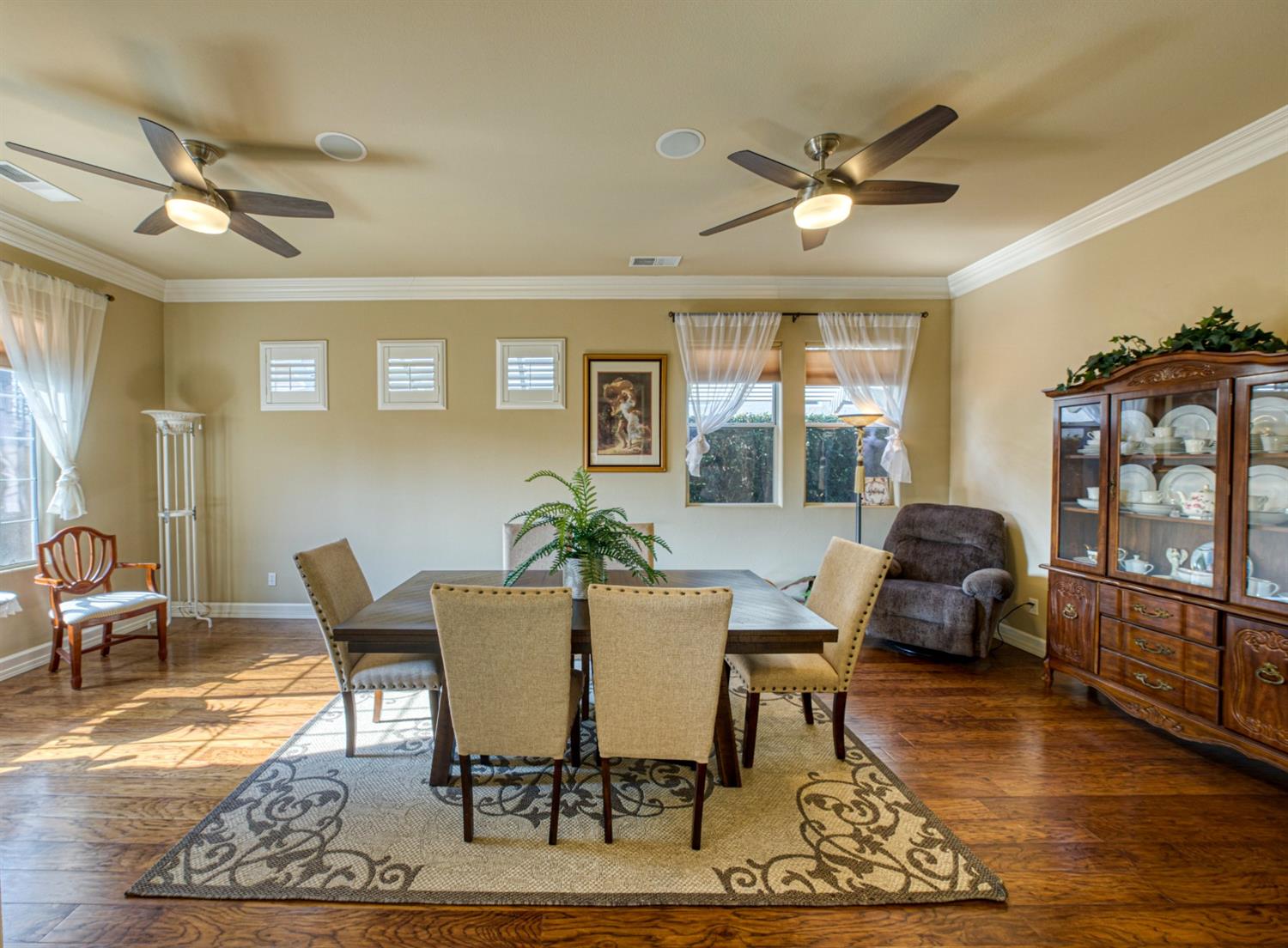 143 West Bedford Avenue Clovis, CA 93611 - Photo 10 of 55 a dining room with wooden floor a chandelier fan a wooden table and chairs