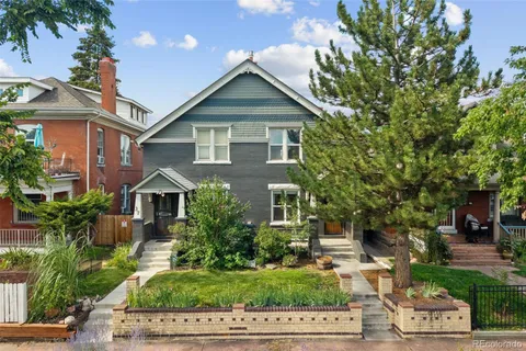 a front view of a house with a yard and potted plants