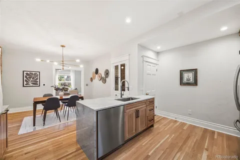 a living room with stainless steel appliances granite countertop furniture wooden floor and a window