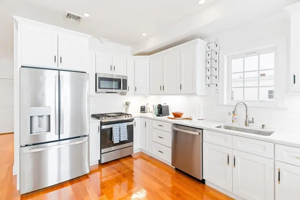 a kitchen with white cabinets stainless steel appliances and a window