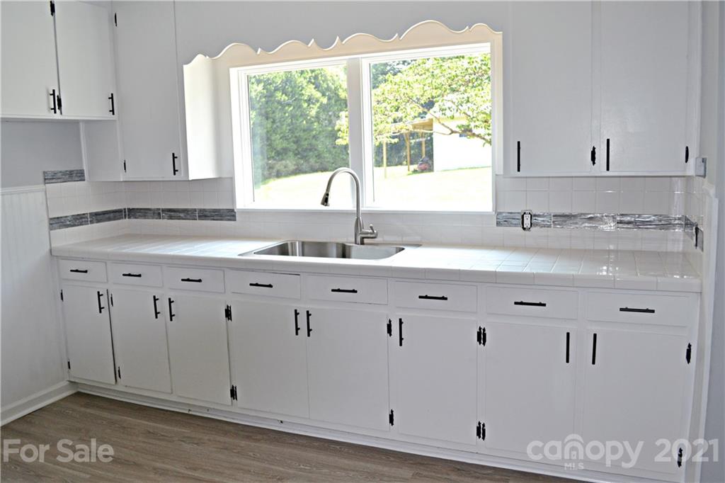 6814 Jenkins Road Morganton, NC 28655 - Photo 6 of 14 a kitchen with granite countertop a sink window and white cabinets