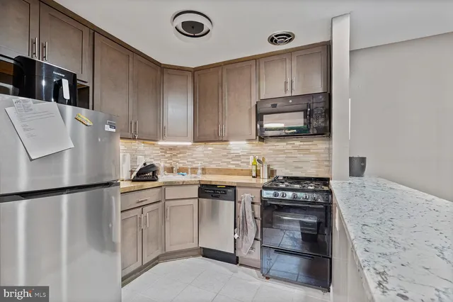 a kitchen with granite countertop a stove sink and refrigerator