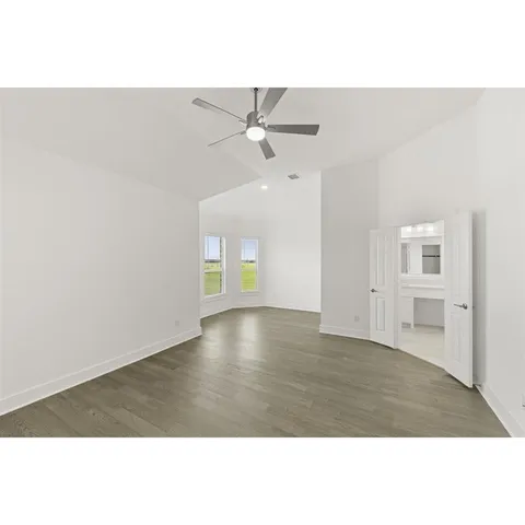 a view of an empty room with window and chandelier fan